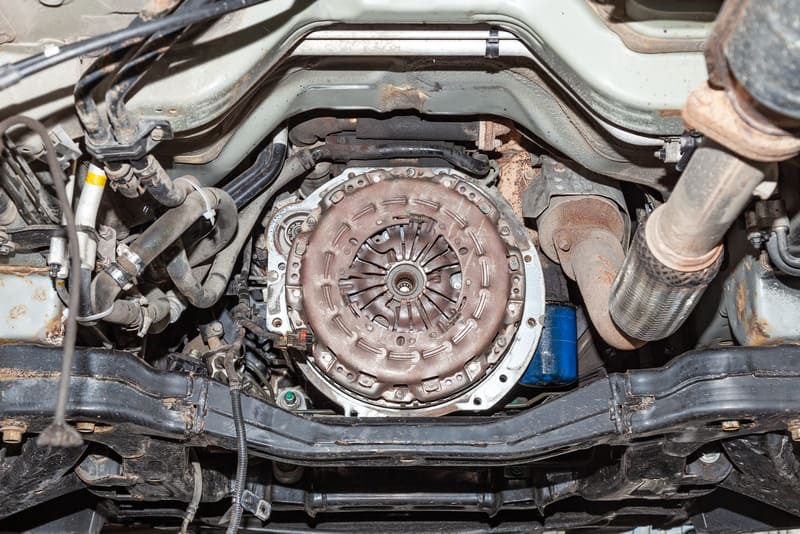View of the car's clutch basket during the repair of a car lifted on a lift in a vehicle maintenance workshop. Industry in the auto service.